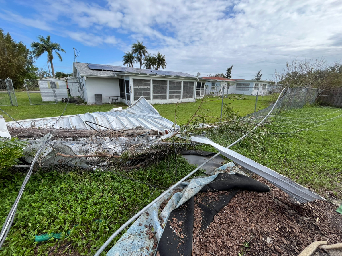 Collapsed metal panels and damaged fencing at a residential property